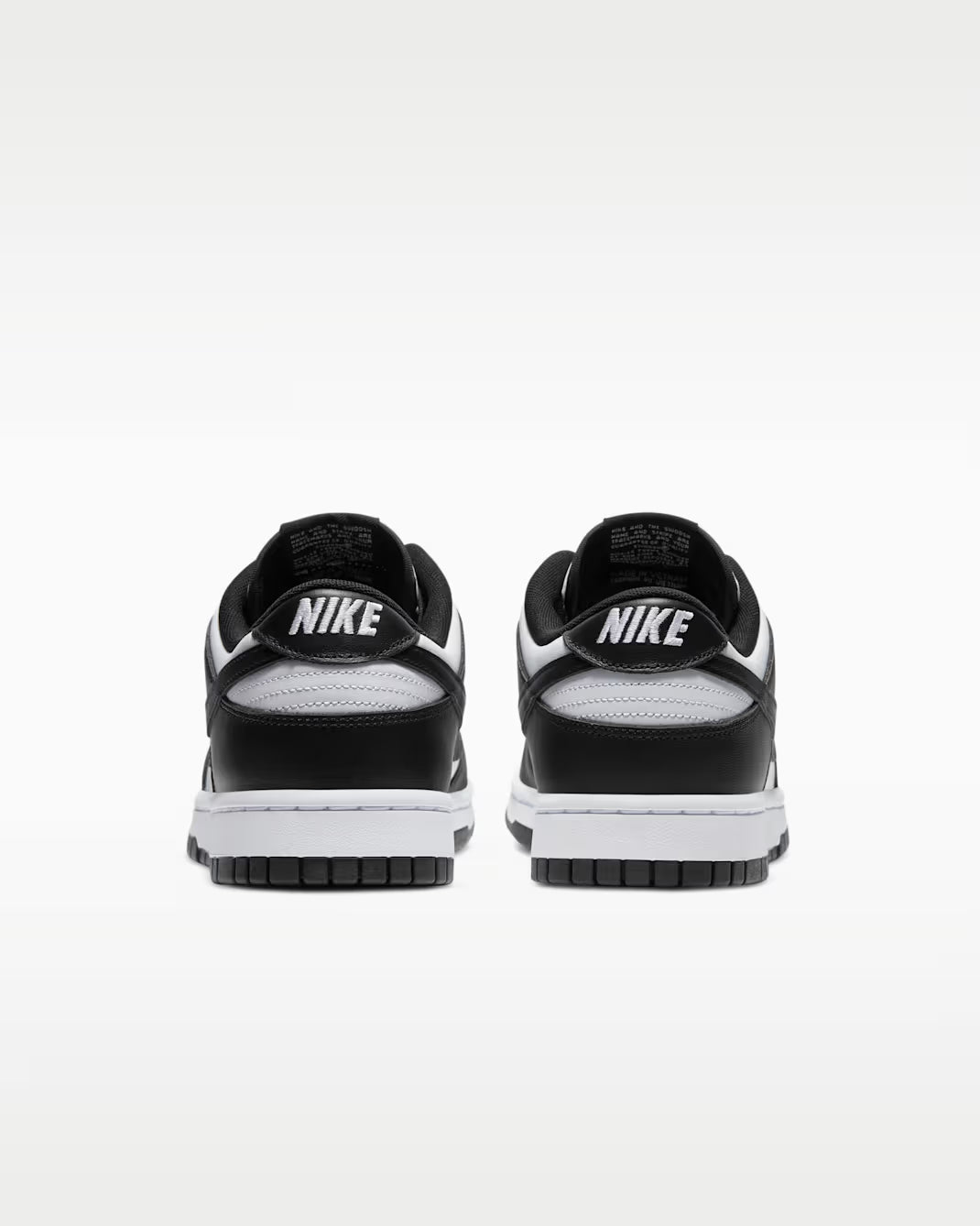 Black and white Nike sneakers shown from the back on a light gray background