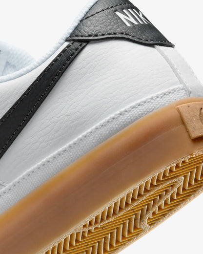 Nike Court Legacy Next Nature sneakers in white with gum yellow outsole and synthetic leather upper. Back view.