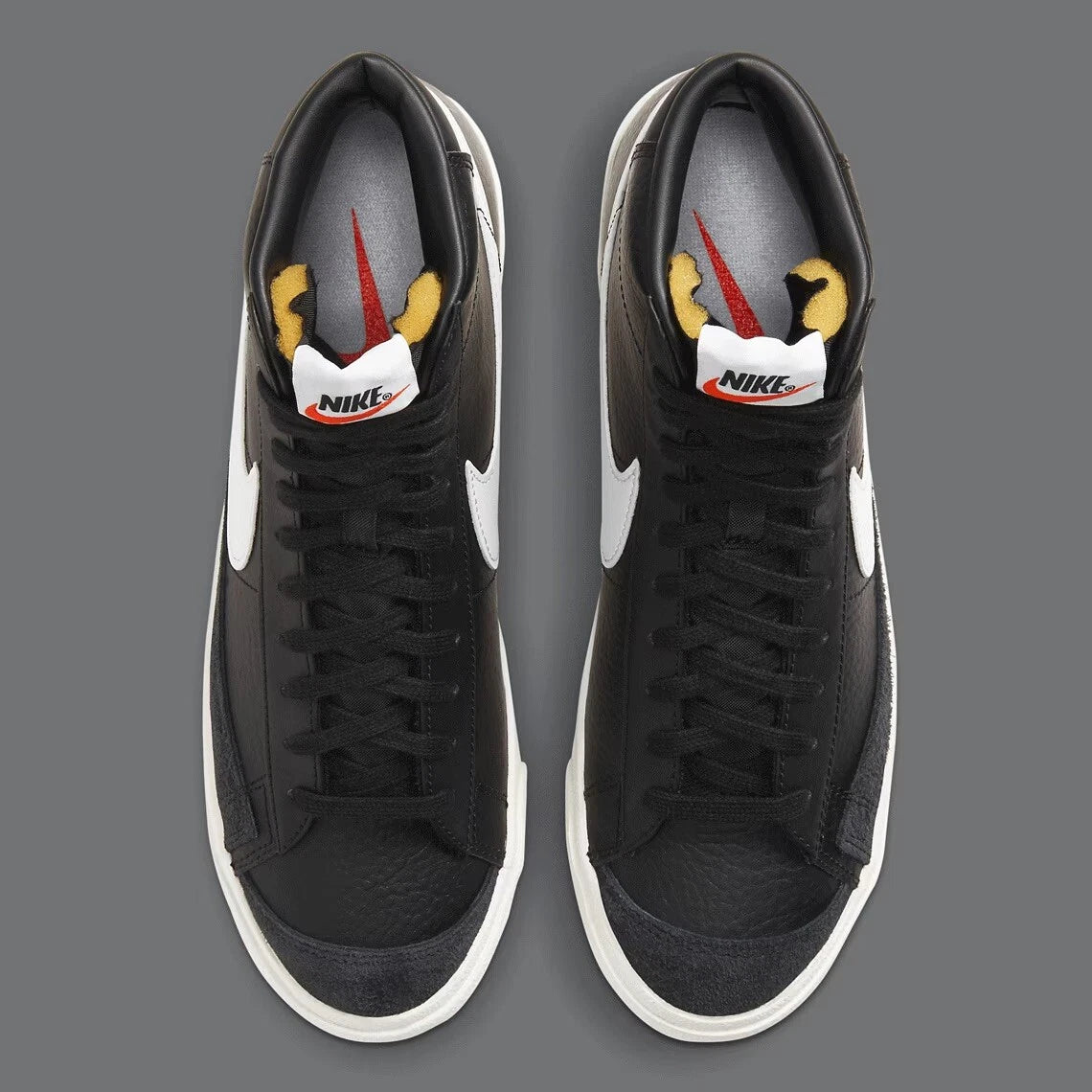 Black Nike sneakers with white swoosh logo on a gray background