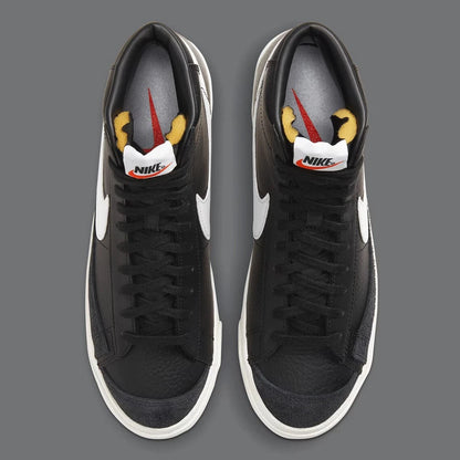 Black Nike sneakers with white swoosh logo on a gray background