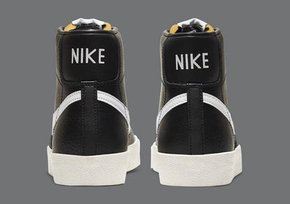 Black Nike high-top sneakers with white soles on a gray background