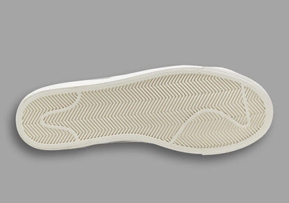 Close-up of a white shoe sole with tread pattern on a gray background